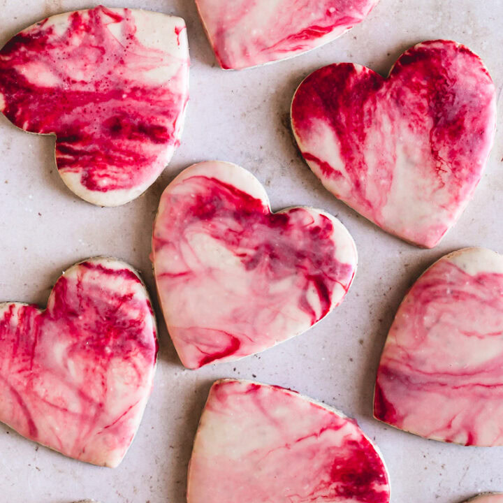 11 heart shaped sugar cookies with red, pink and white marble icing