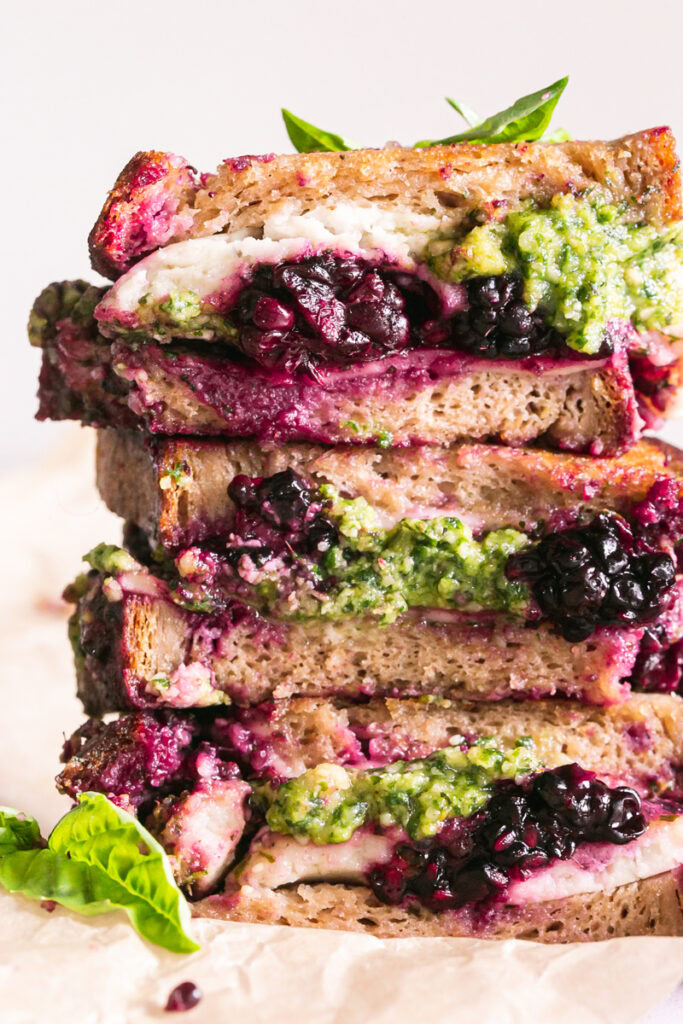 vertical close up image of vegan blackberry pesto grilled cheese sandwich stacked on top of one another