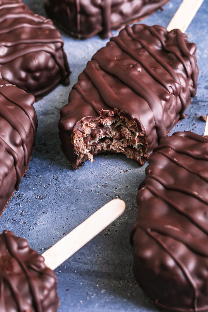 chocolate covered krispy crunch pops one with a bite taken out of it