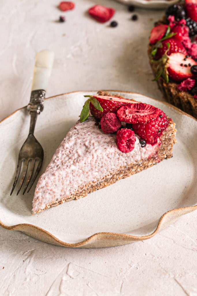 a slice of slices of breakfast chia yogurt granola tart decorated with fresh berries on a plate with a fork
