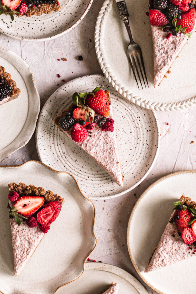 close up of slices of breakfast chia yogurt granola tart decorated with fresh berries on plates