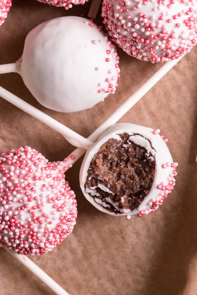 close up flatlay shot of no bake cherry cake pops, one with a bite taken out of it