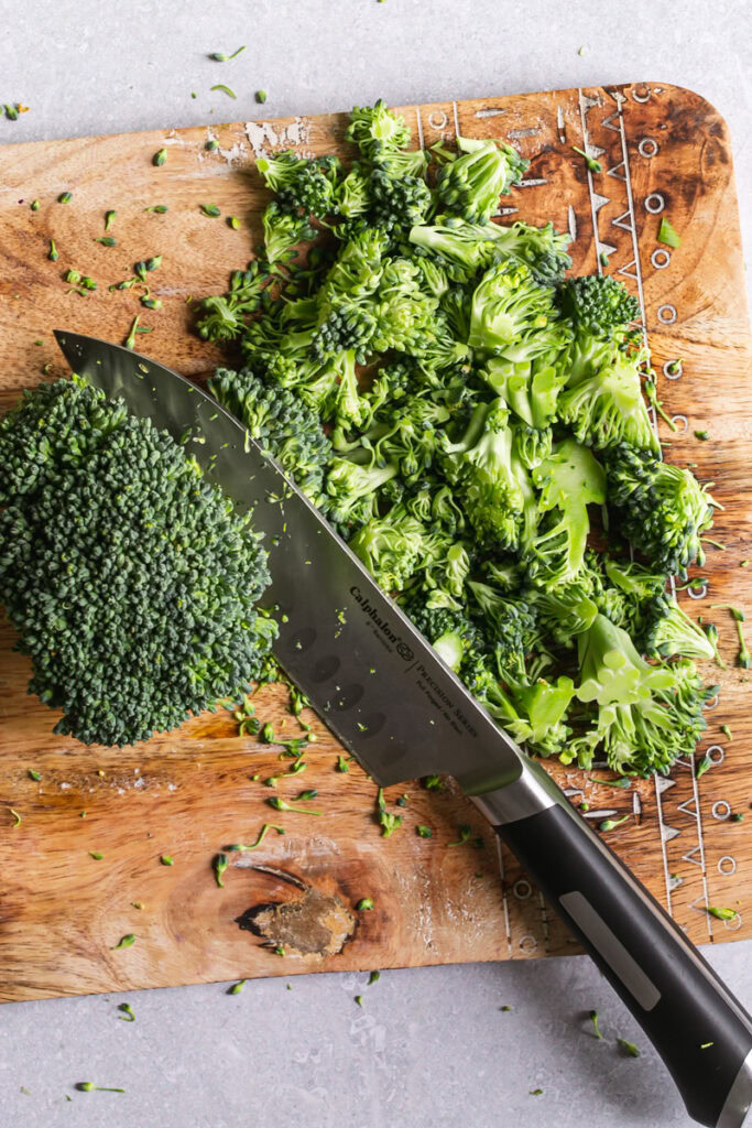 Calphalon 6" santoku knife on a cutting board with chopped broccoli