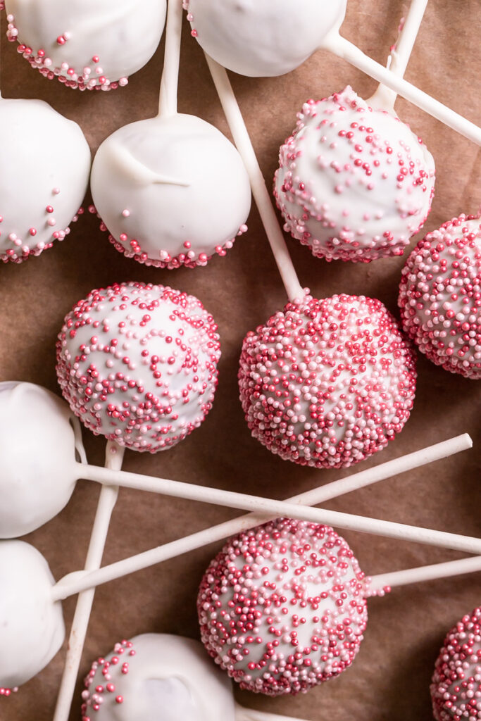 close up overhead shot of cherry cake pops layed out on a parchment-lined baking sheet