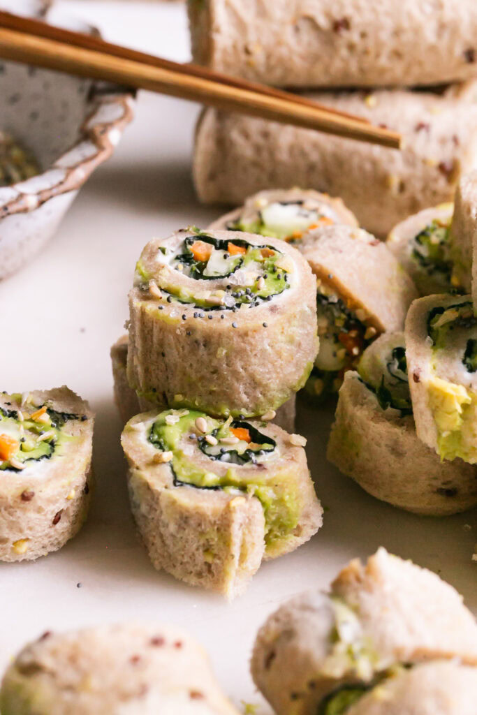 3/4 shot of sliced eggie sushi sandwich rollups stacked on top of each other
