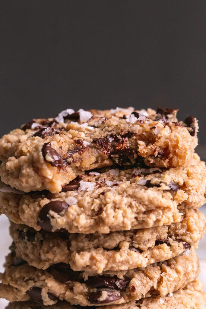 a close up of the stack of flourless salted tahini chocolate chip cookies with a bite taken out of the top one
