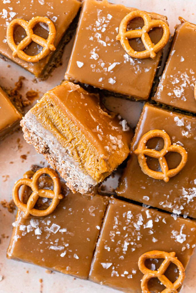 a close up overhead shot of sliced Salted Caramel Pumpkin Pie Bars, the middle one flipped on its side to reveal the pumpkin filling 