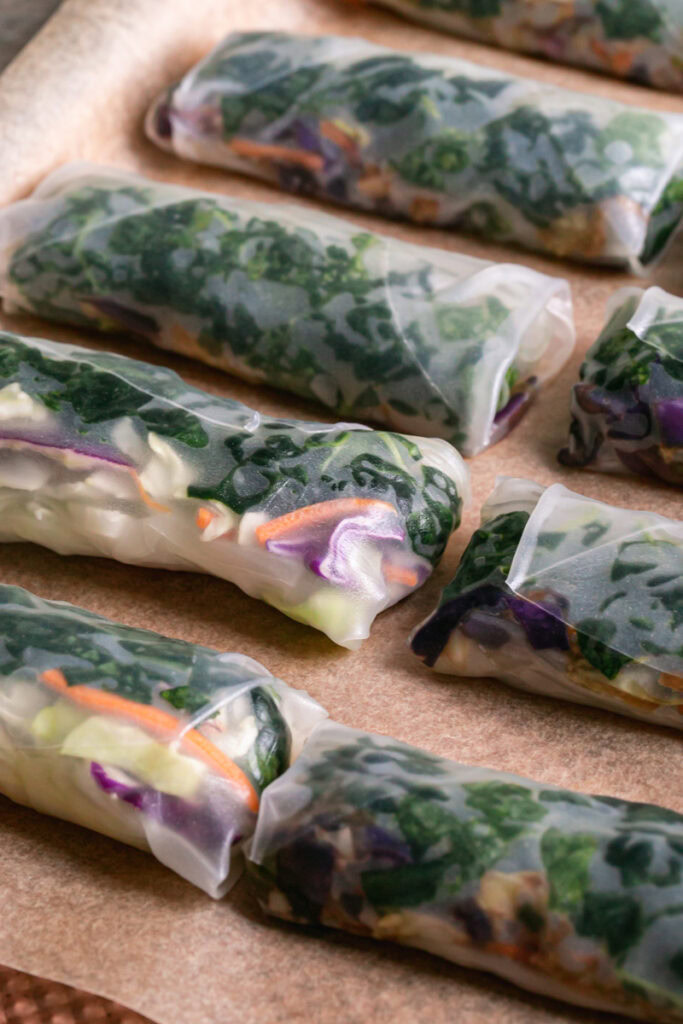 spring rolls rolled up laid out on a baking sheet lined with parchment paper