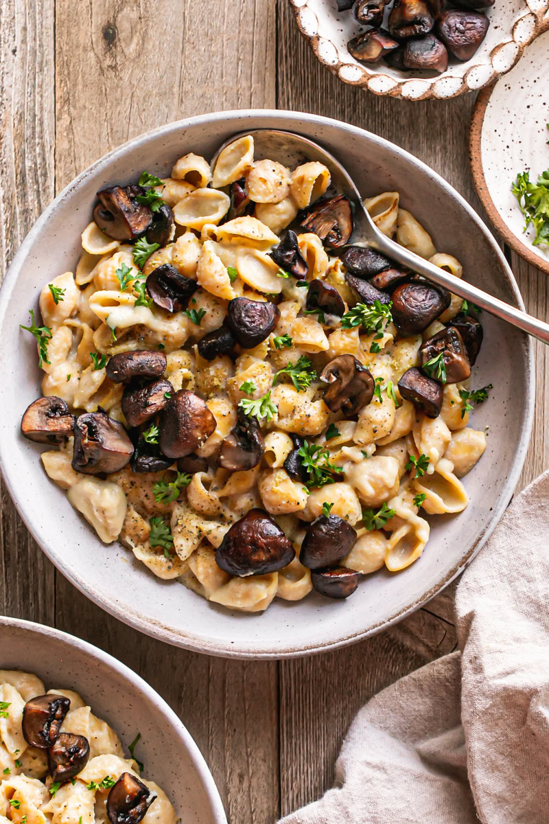a bowl of Creamy Alfredo Style Mushroom Pasta with another bowl peeking in on the lower left corner with a linen napkin in the lower right