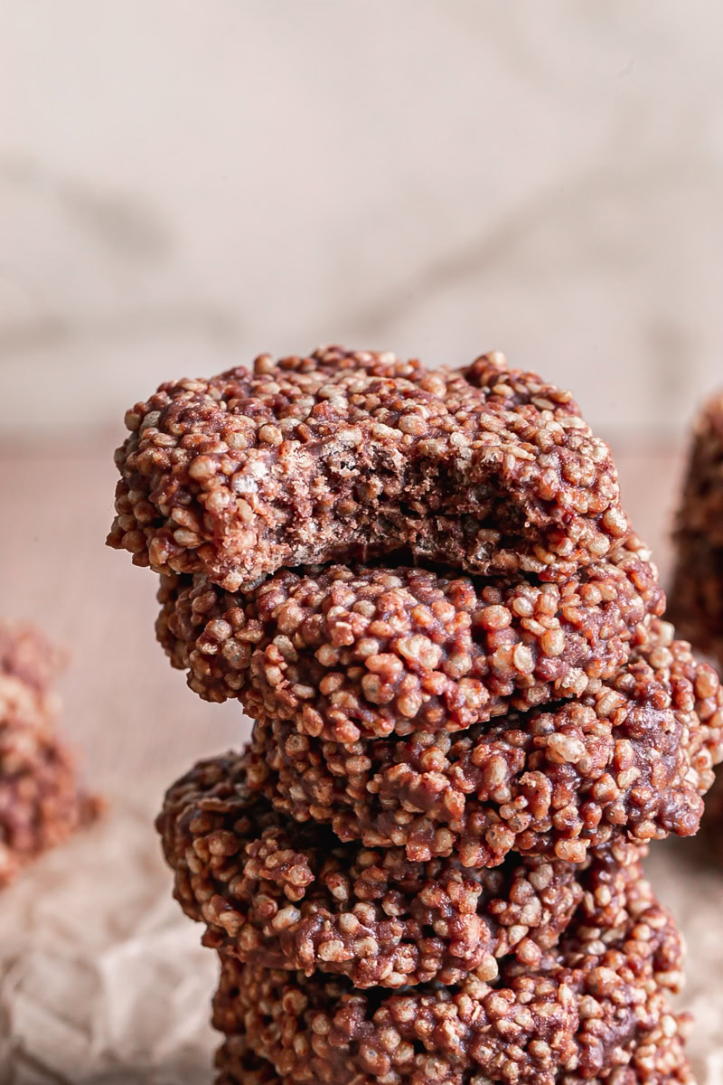 close up of Crispy Quinoa Cacao Cookies stacked on top of one another, the top one with a bite taken out of it