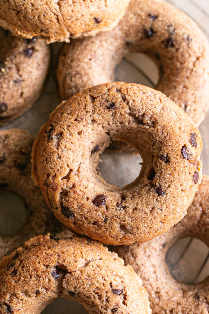 close up of grain-free banana bread donuts piled on a round wire cooling rack