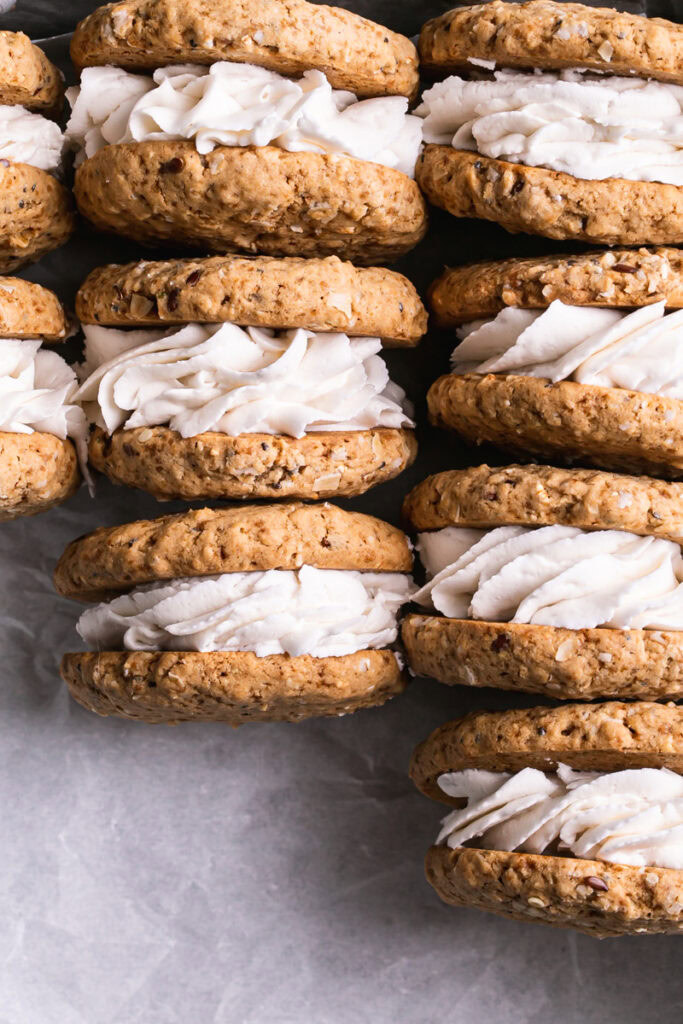 flatlay image of oatmeal sandwich cookies filled with frosting laid out in a row