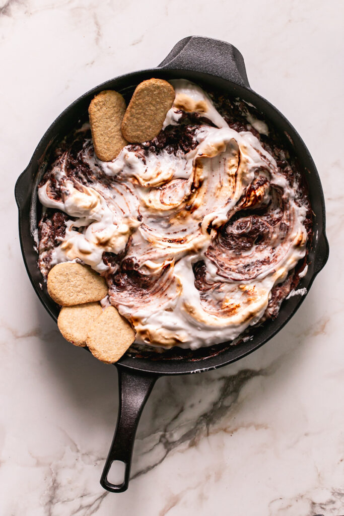 Vegan Cast Iron S'mores Dip in a Calphalon cast iron skillet with toasted vegan marshmallow fluff and gluten-free graham crackers laid inside the skillet