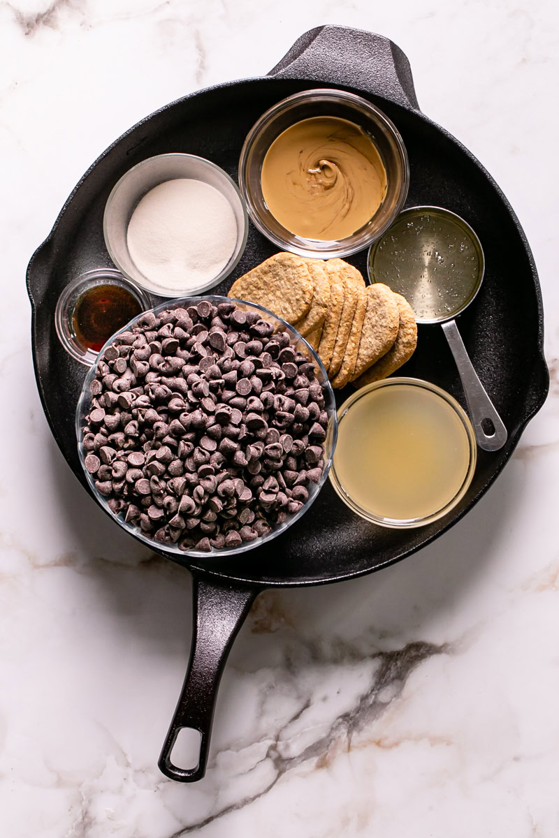 all of the ingredients used to make this vegan s'mores dip inside of a calphalon cast iron skillet