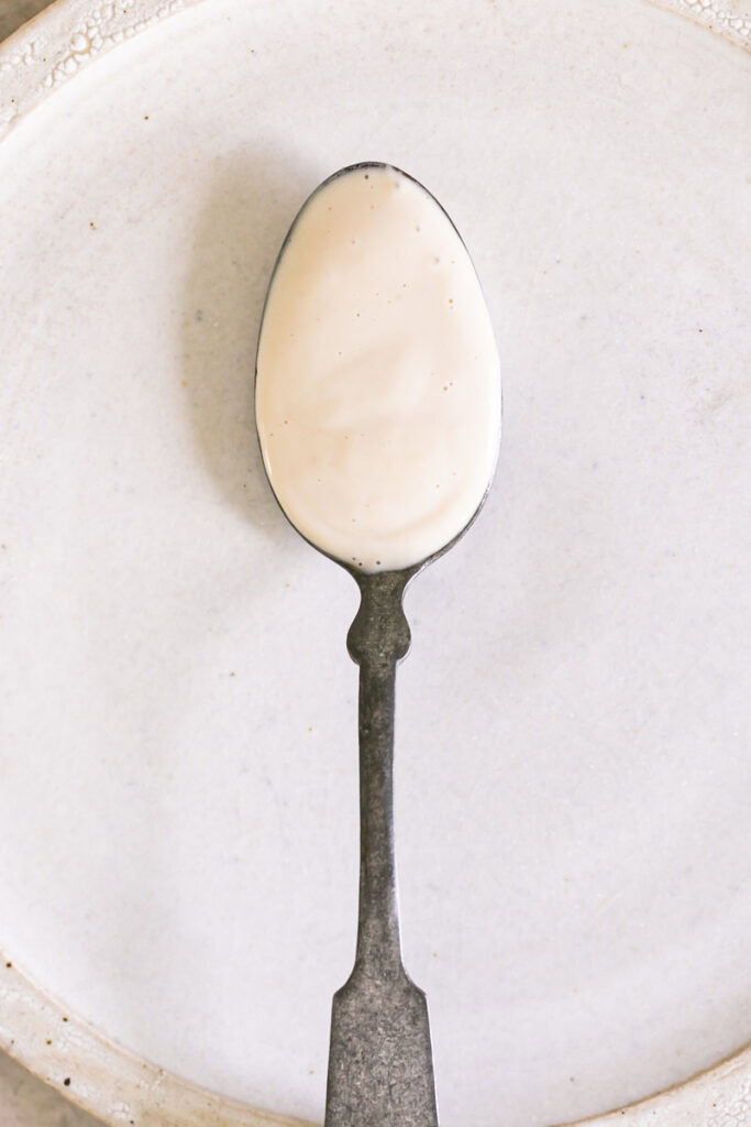 creamy tahini dressing on a spoon on a plate