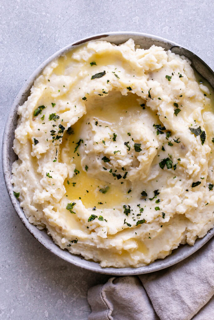 a bowl of Dairy-Free Mashed Potatoes with melted dairy-free butter and garnished with chopped parsley