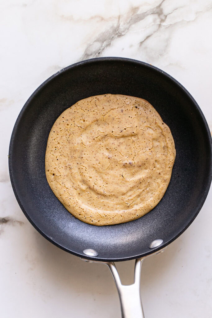 the vegan gluten-free savory pancake batter cooking in a pan