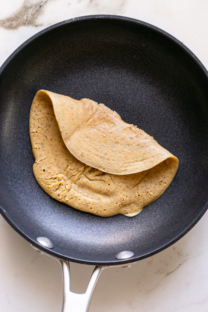 a vegan gluten-free savory pancake in a skillet folded over