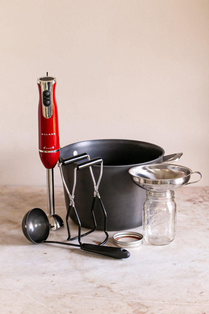 tools needed to make canned salsa, a large stock pot, ladle, immersion blender, canning tongs, canning jar, lid and band, and canning funnel