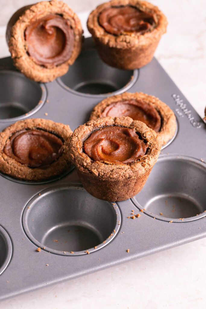 baked pumpkin pie cookie cups undecorated on top of a calphalon muffin pan